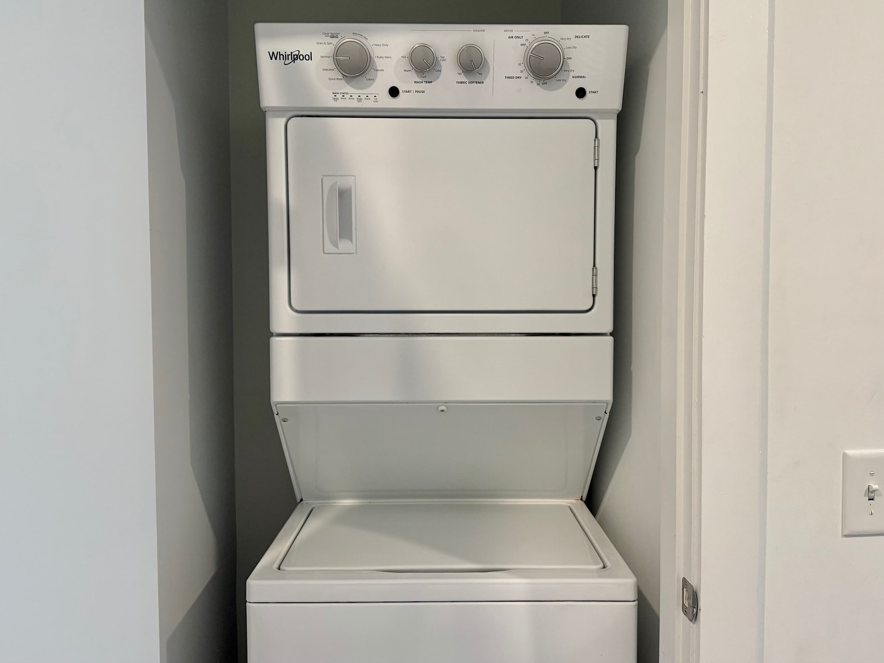 A Whirlpool washer and dryer stacked in a small laundry room.
