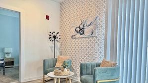 Una sala de estar moderna con dos sillones cómodos, una mesita redonda y un elemento decorativo en la pared.