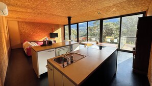 Eine moderne Küche mit einer großen Kochinsel, einem eingebauten Geschirrspüler und Blick ins Freie durch große Fenster.