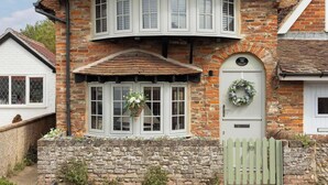 A two-story house with a brick facade, a green gate, and a white door with a wreath. - Cosy Character Cottage by the Sea (East Wittering)