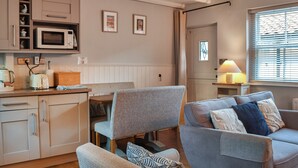 Een gezellige woonkamer met een bank, stoelen en een keukenhoek met een magnetron en broodrooster.
