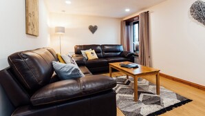 A modern living room with a leather sofa, a wooden coffee table, and a patterned rug. - 3 bedroom accommodation in near Gatehouse of Fleet (near Gatehouse of Fleet)