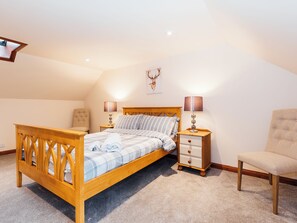 Une chambre à coucher avec un lit en bois, deux tables de chevet, une chaise et une œuvre d’art accrochée au mur.