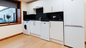 A modern kitchen with white cabinets, a black countertop, a washing machine, a dishwasher, and a refrigerator. - 3 bedroom accommodation in near Gatehouse of Fleet (near Gatehouse of Fleet)