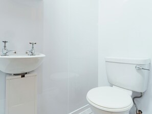 Ein Badezimmer mit einem weißen Waschbecken, zwei Wasserhähnen und einer Toilette.