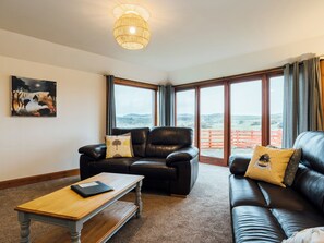 A living room with a leather sofa, a wooden coffee table, and a painting on the wall.