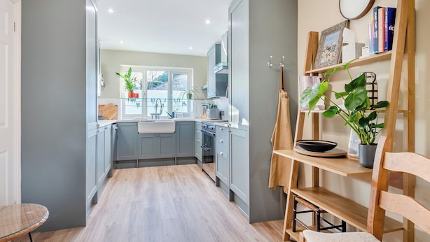 Una cocina moderna con armarios grises, piso de madera y vistas al exterior.