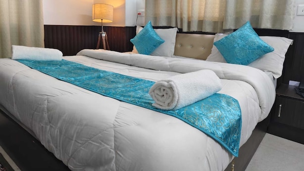 A hotel room with a large bed, a bedside lamp, and a view of the outdoors through sheer curtains. - OnlyStay Silicon Inn Shimla (Shimla)