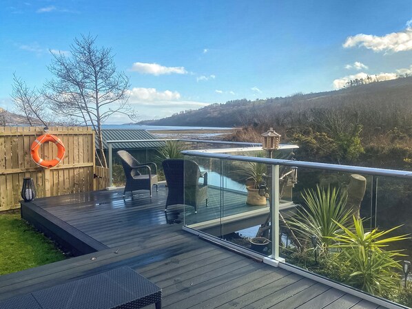 Terraza con mobiliario exterior, un flotador y vistas al mar y colinas.