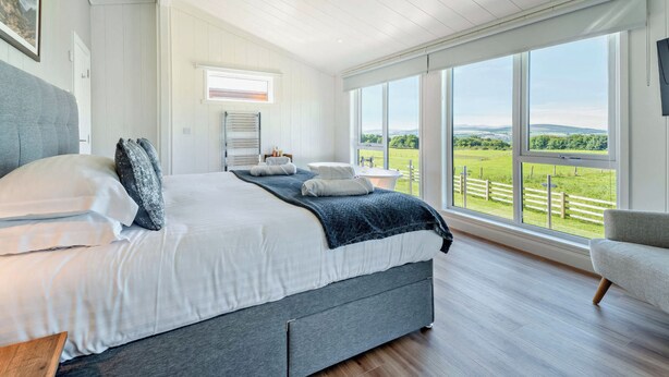 Un dormitorio con cama, ventana, vistas al exterior y una araña.