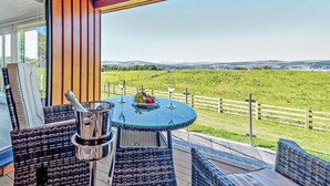 Un espacio al aire libre cubierto con una mesa, sillas y vistas a un paisaje verde.