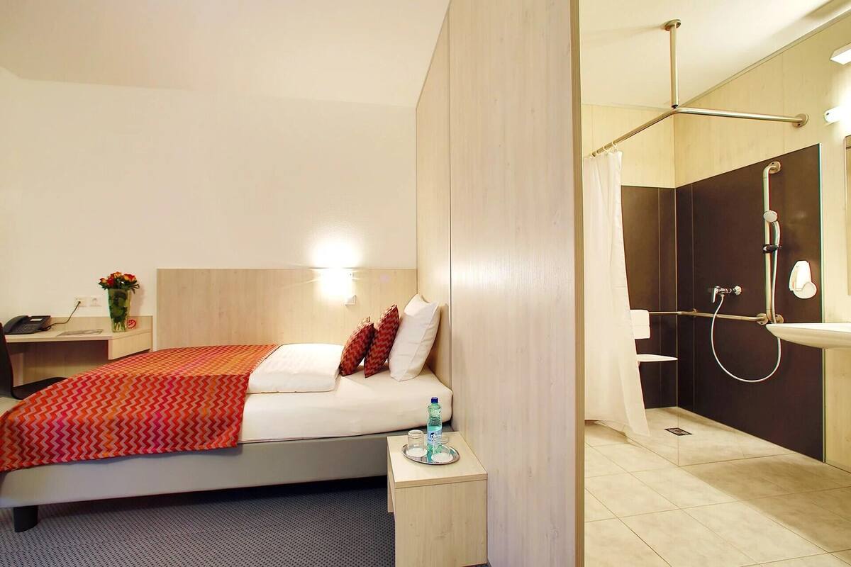 Une chambre d’hôtel comprenant un lit, une table de chevet et un espace douche.