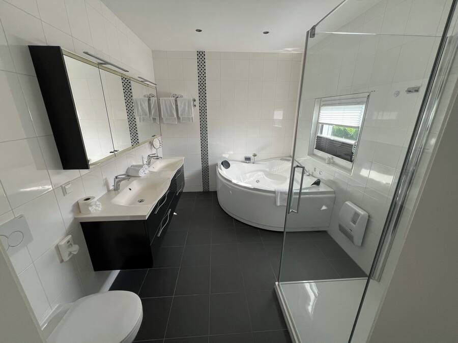 Un baño moderno con una bañera grande, una zona de ducha independiente y un inodoro.