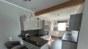 Una cocina moderna con una isla central, electrodomésticos integrados e iluminación colgante.
