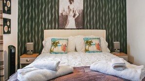 A neatly made bed with two pillows, a headboard, and a wall with a patterned wallpaper.