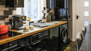 A modern kitchen with a built-in oven, a coffee machine, a washing machine, and a window with a view of the outside.