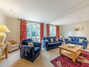 A living room with two blue sofas, a wooden coffee table, and a patterned rug. - Carriage House - UK49288 (Doxford, near Embleton)