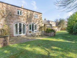 Une maison en pierre avec un patio, une table à manger et des chaises.