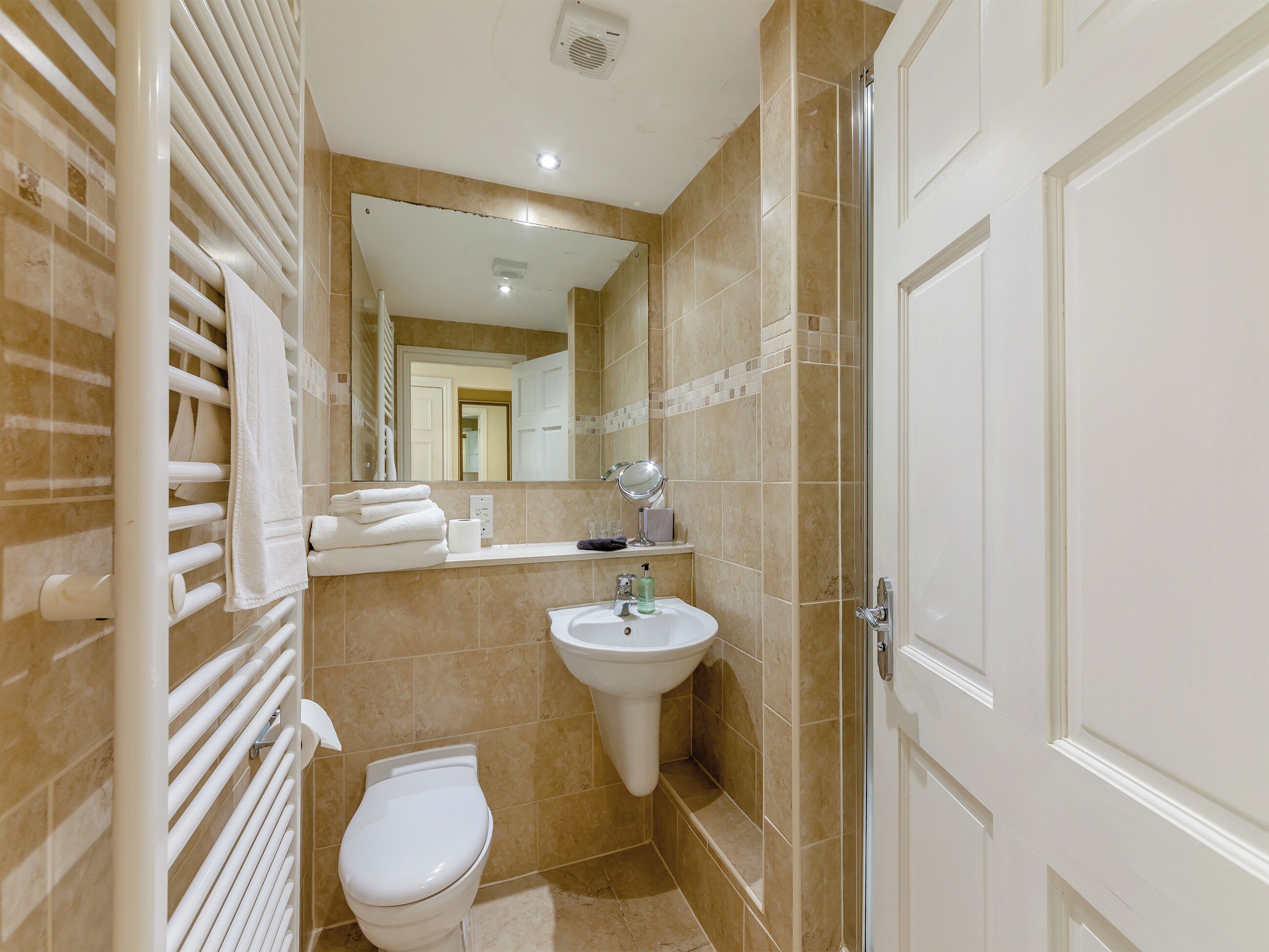 Un baño con inodoro, lavabo, toallero y zona de ducha.