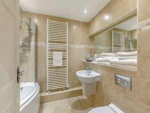 Une salle de bain moderne équipée d’une baignoire, d’un lavabo, d’un miroir et d’un porte-serviettes.
