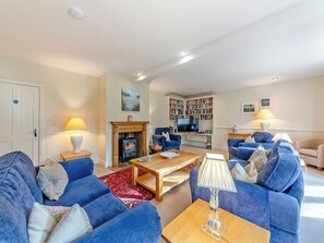A living room with blue sofas, a fireplace, a bookshelf, and a television.