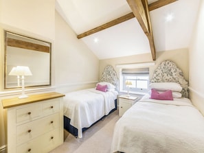 A bedroom with two beds, a dresser, a mirror, and a window with a view.