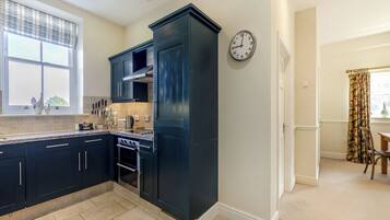A modern kitchen with dark cabinetry, a built-in oven, and a window with decorative items.