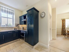 Una cocina moderna con armarios oscuros, horno empotrado y una ventana decorada.