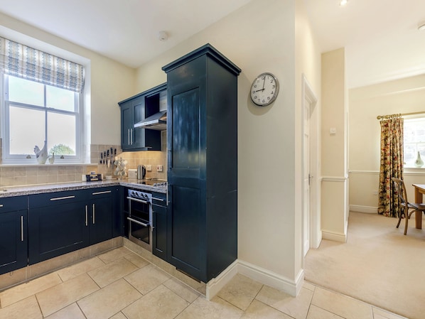 A modern kitchen with dark cabinetry, a built-in oven, and a window with decorative items.
