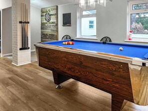 Een biljart met ballen, een dartbord en een raam met uitzicht.