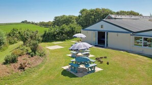 A house with a patio area, a covered seating area, and a view of a green field. - Goldfinch Apartment - UK49296 (Woolfardisworthy, Clovelly)