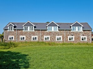 A large stone building with multiple windows and a sloped roof. - Goldfinch Apartment - UK49296 (Woolfardisworthy, Clovelly)
