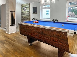 Een pooltafel met ballen, een dartbord en een schoolbord.