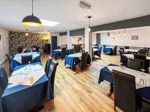 Een restaurant met gedekte tafels, stoelen en hangende hanglampen.
