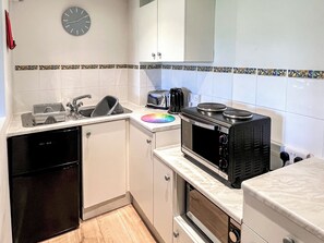 Een keuken met een vaatwasser, een broodrooster, een magnetron en een klok aan de muur.