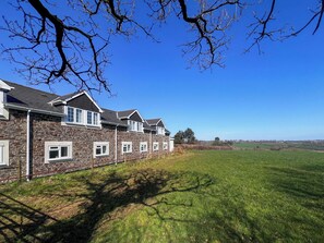 Een rij stenen huizen met veel ramen en een grasveld op de achtergrond.