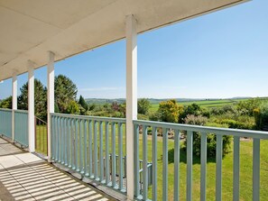 A covered outdoor area with a view of a green landscape.
