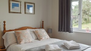 Un lit bien fait, avec des oreillers, une lampe de chevet et une fenêtre avec des rideaux.
