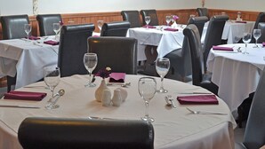 Un restaurant avec des tables rondes, des chaises en cuir noir, des nappes blanches et des œuvres d’art encadrées accrochées aux murs.