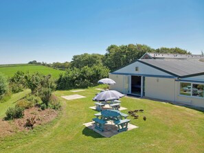 Una casa con patio, una zona de estar techada y vistas a un campo verde.