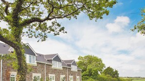 A stone building with multiple windows and a large tree in front. - Chaffinch Apartment - UK49307 (Woolfardisworthy, Clovelly)