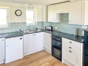 A modern kitchen with white cabinets, a dishwasher, a stove, and a toaster.