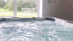 Ein Whirlpool mit Blick auf eine Rasenfläche und einen weißen Gartenstuhl.