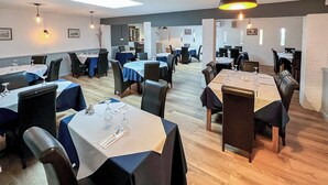 A restaurant with multiple tables, chairs, and pendant lighting. - Jasmine Apartment - UK49309 (Woolfardisworthy, Clovelly)
