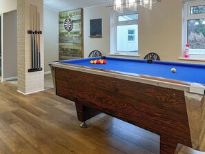 Une table de billard avec des billes, un jeu de fléchettes et un tableau noir.