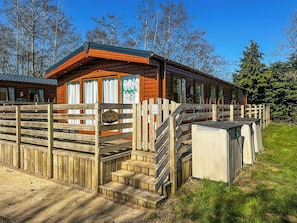 A wooden cabin with a porch, a sign indicating 'Phoenix', and a small outdoor area with steps leading to the entrance.