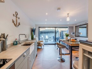 A modern kitchen with a dining area, large windows, and a view of the backyard.