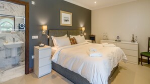 A hotel room with a bed, bedside tables, a mirror, a sink, and a framed picture on the wall.