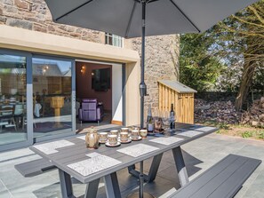 An outdoor patio with a table set for dining, a large umbrella, and a stone building in the background. - 5 bedroom accommodation in Duns (Duns)