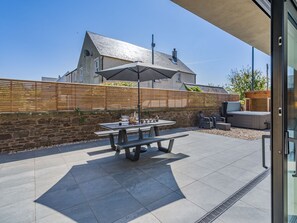 A patio with a table and chairs, a hot tub, and a stone wall. - 5 bedroom accommodation in Duns (Duns)